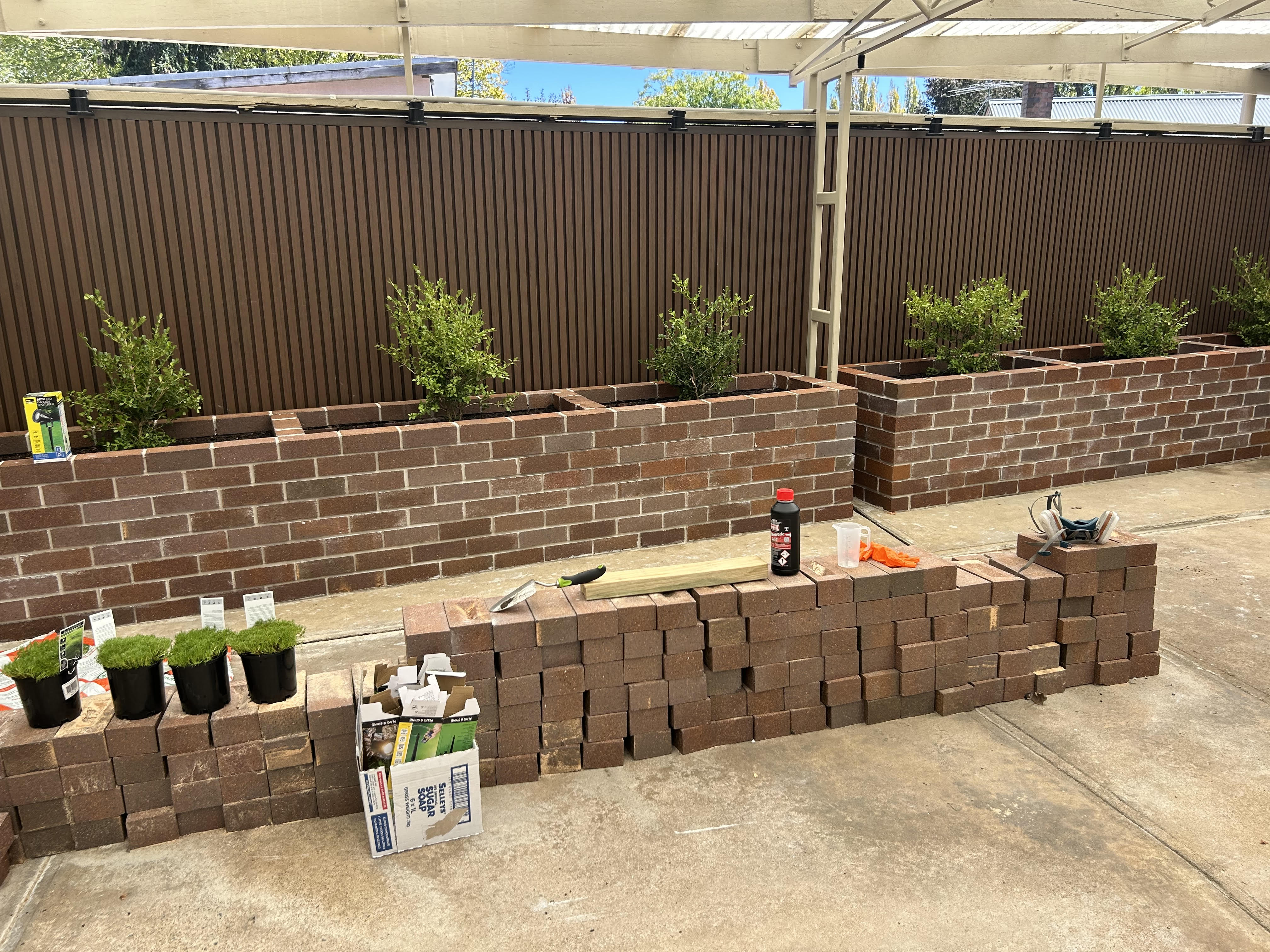 Raised brick garden beds being built at an Asina SIL home